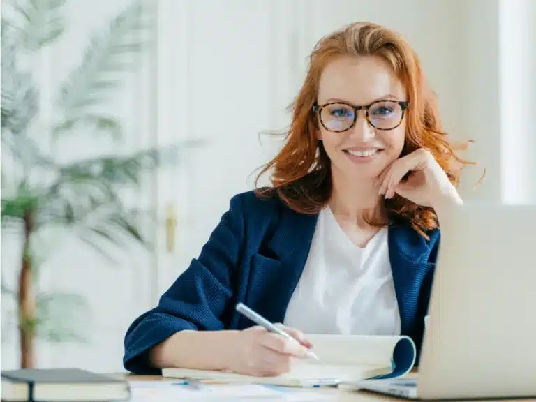 A smiling woman is working at her salesforce invoicing.