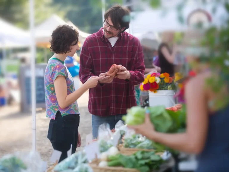A couple is looking at produce at a farmers market