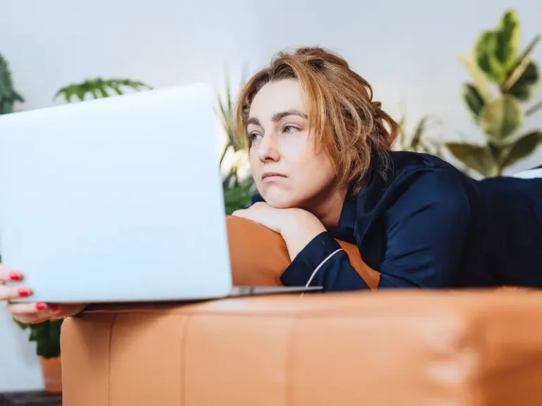 A woman who looks very tired stares at her laptop.