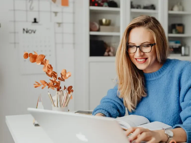 A woman is working on her laptop. She is smiling.