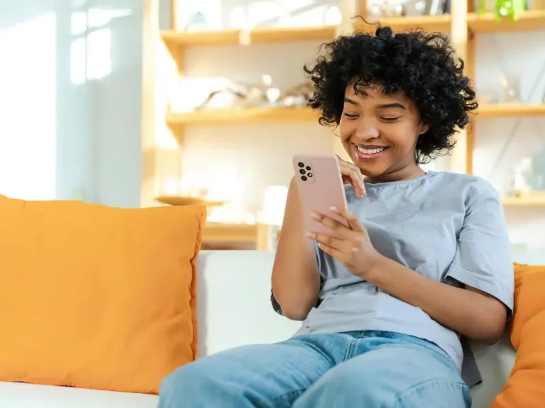 A person is sitting on a couch surfing the web on their smartphone.