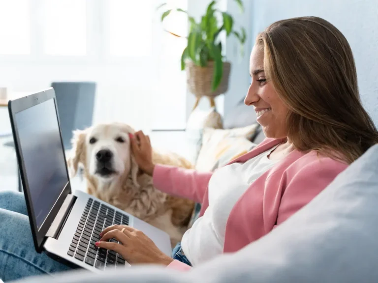 A woman and her dog sit on the couch and shopping online.