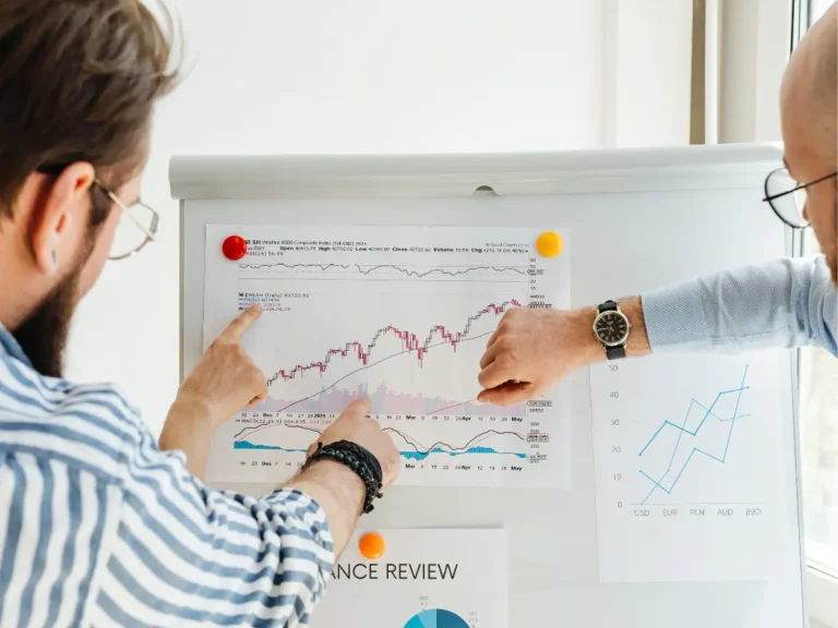 Two people work over documents and analytics graphs