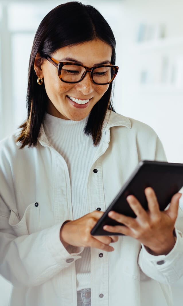 A woman with glasses looking at a tablet