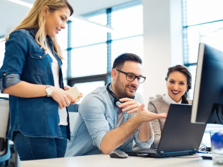 Three colleagues are discussing a topic at their work desk.