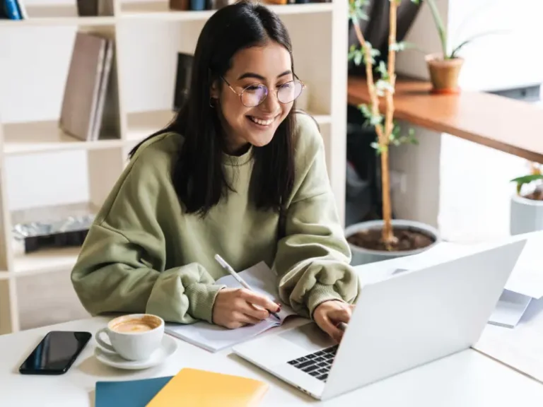 A smiling woman works at a laptop.