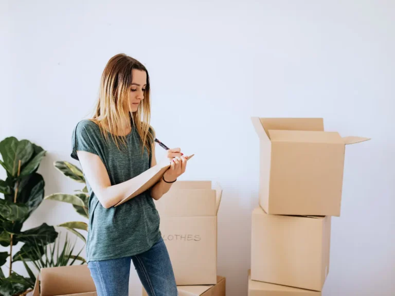A woman is checking a list while standing in front of moving boxes, symbolizing a software migration plan.