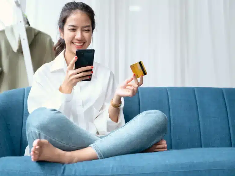 A woman is sitting on her couch and purchasing something via agentic commerce
