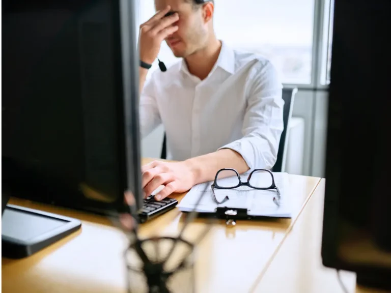 A man - visibly frustrated - sits at his work desk.