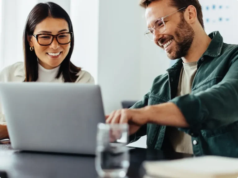 Two people are reading something on a laptop.
