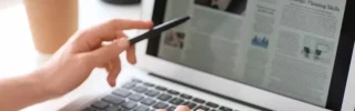 A person reads a newspaper on their laptop