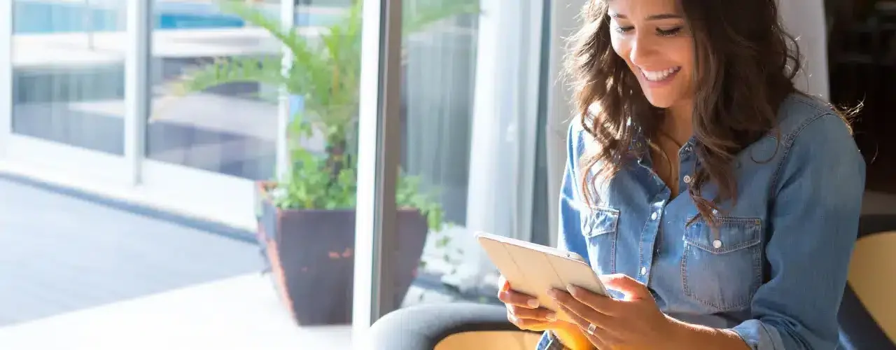 A woman is reading on a tablet.