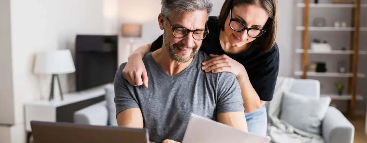 A woman and a man look at their tax papers in front of a computer